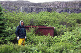Willie Kumarluk standing in front of a large iron tank used for boiling whale blubber on the site of Little Whale River Post (GlGe-9) (Photo by Christian Roy)